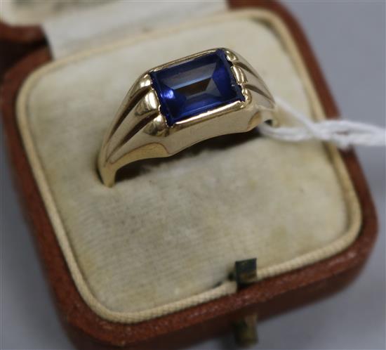 A yellow metal and synthetic blue sapphire dress ring with fluted shoulders, size S.